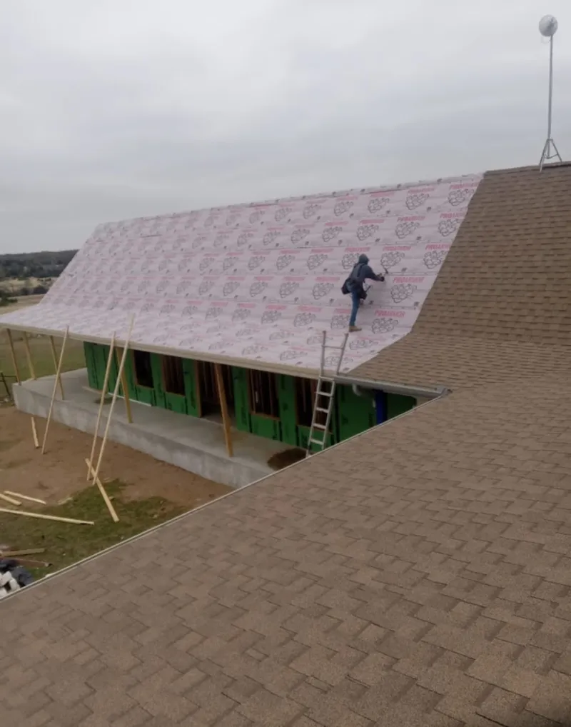 Worker preparing underlayment for a metal roof installation in Jeannette